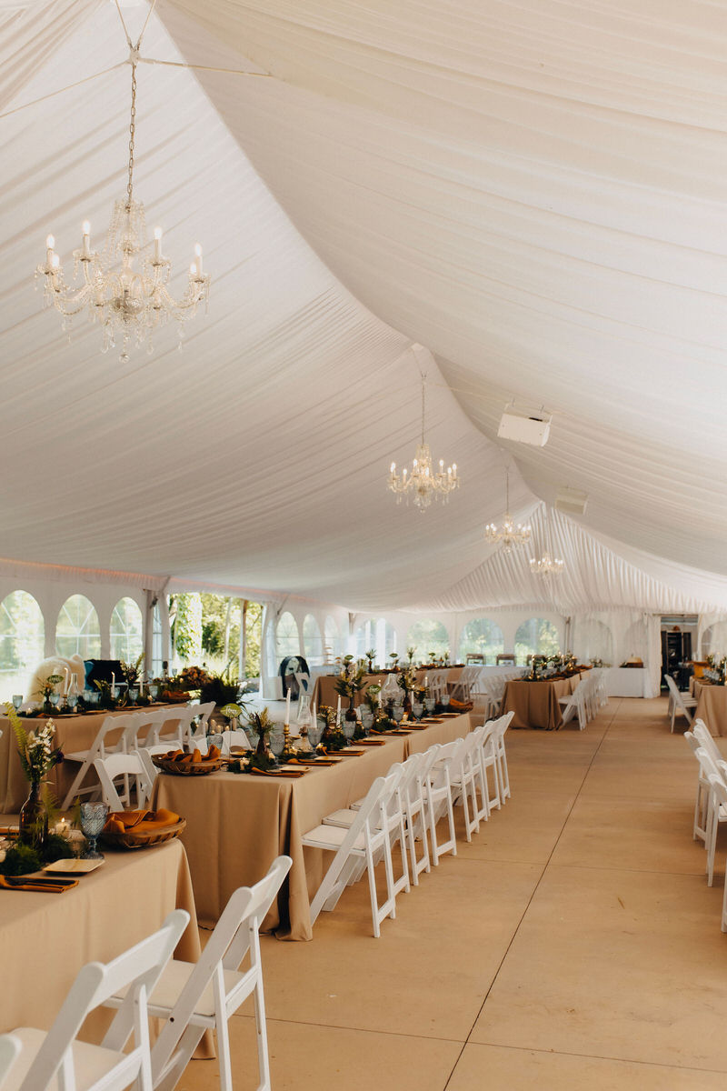 inside an elegant tent with large tables and chairs set up 
