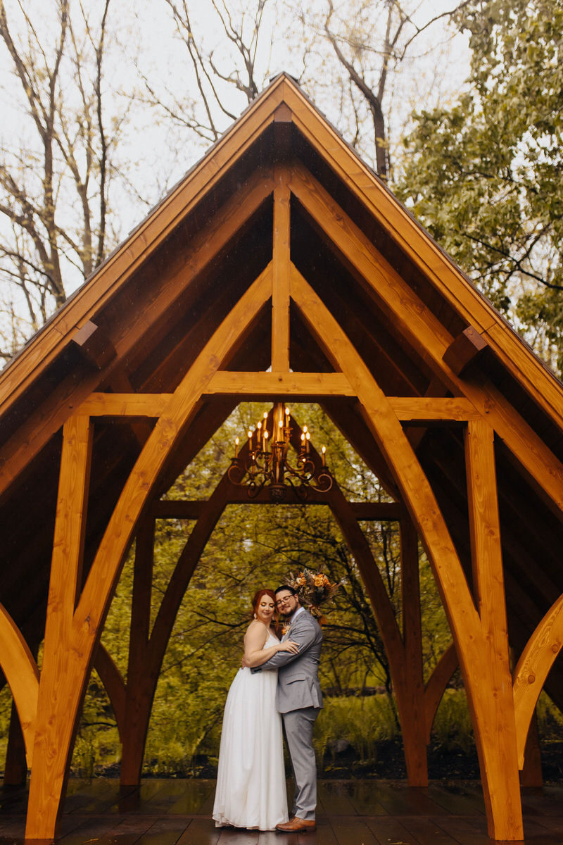 couple standing under large wood covering