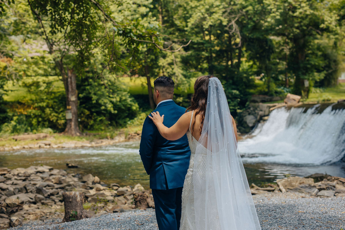 Celebrant with their hand on their to-be-wed's shoulder in front of a small waterfall