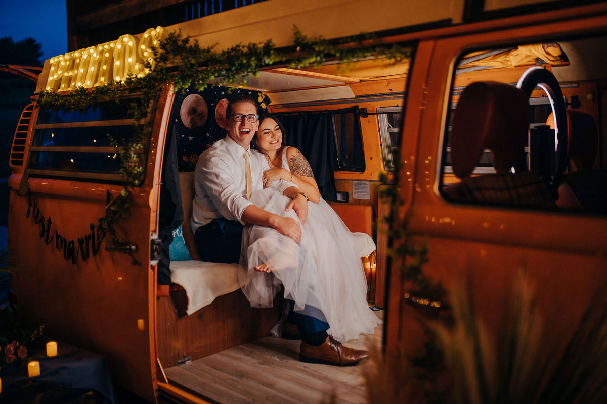 Couple sitting in a van smiling on their wedding day