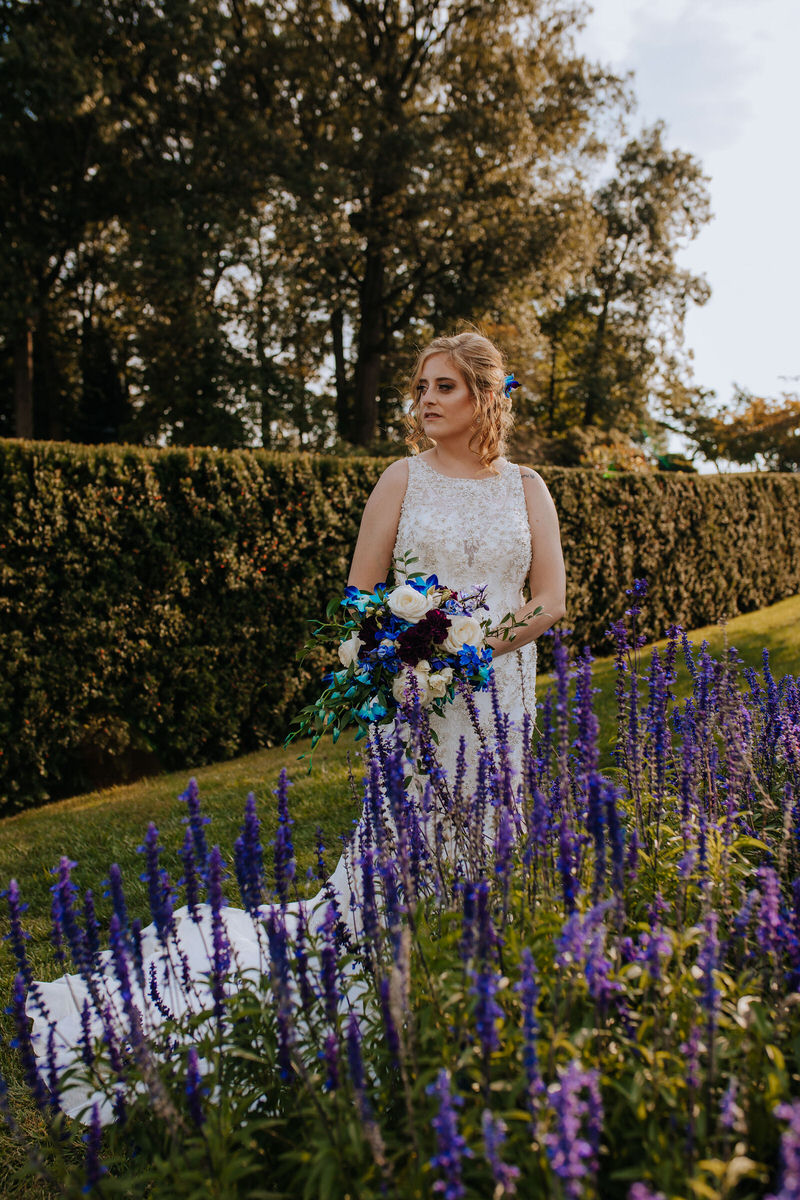 Celebrant standing in a garden with purple flowers in front of them