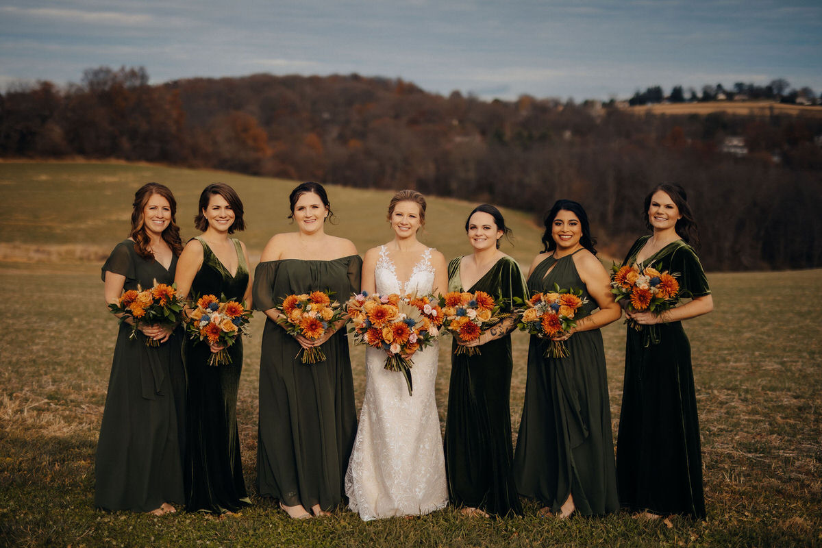 Wedding party smiling while standing in a large field 