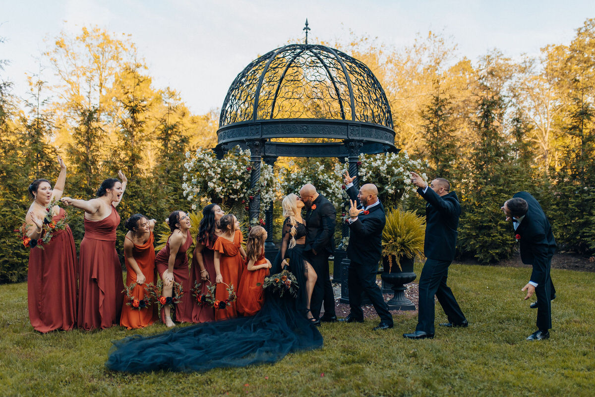 couple kissing with their wedding party on either side of them