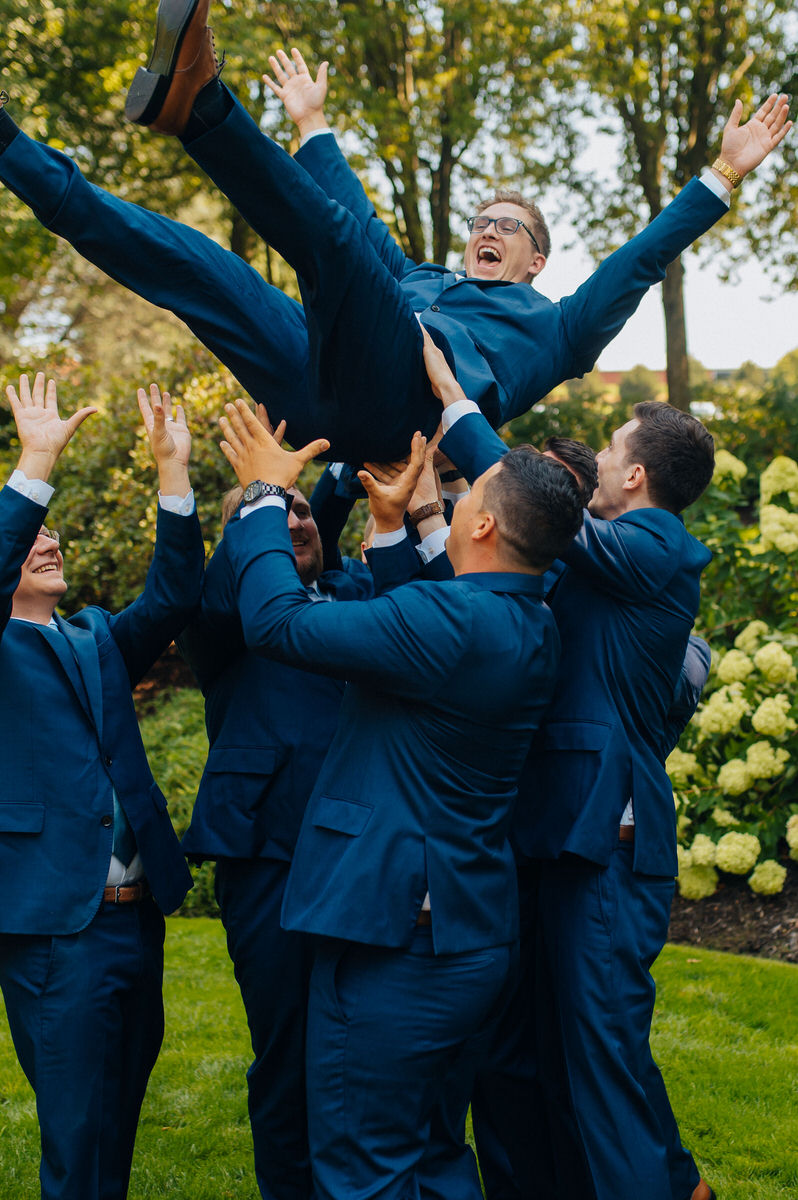 Wedding party throwing celebrant up in the air