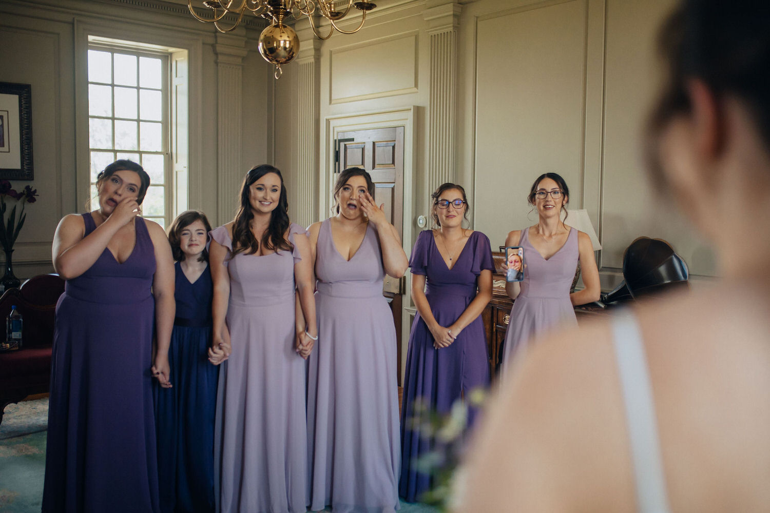 People in purple dresses crying during a first look.