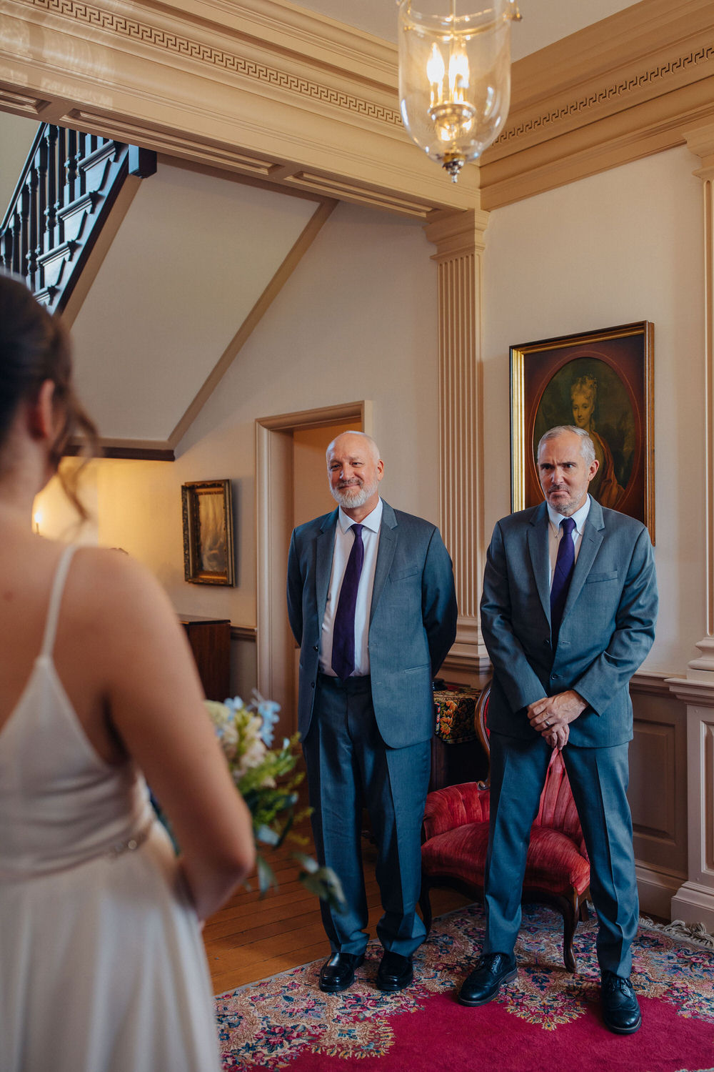Image of two people looking at a celebrant in white dress for a first look.