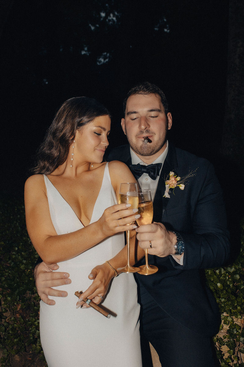 married couple smoking cigars and toasting with champagne glasses