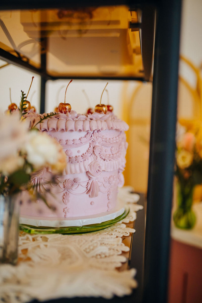 pink cake with a vase of flowers in front of it