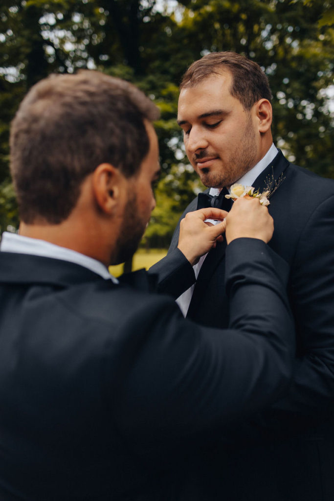 wedding party member pinning flower on suit jacket 