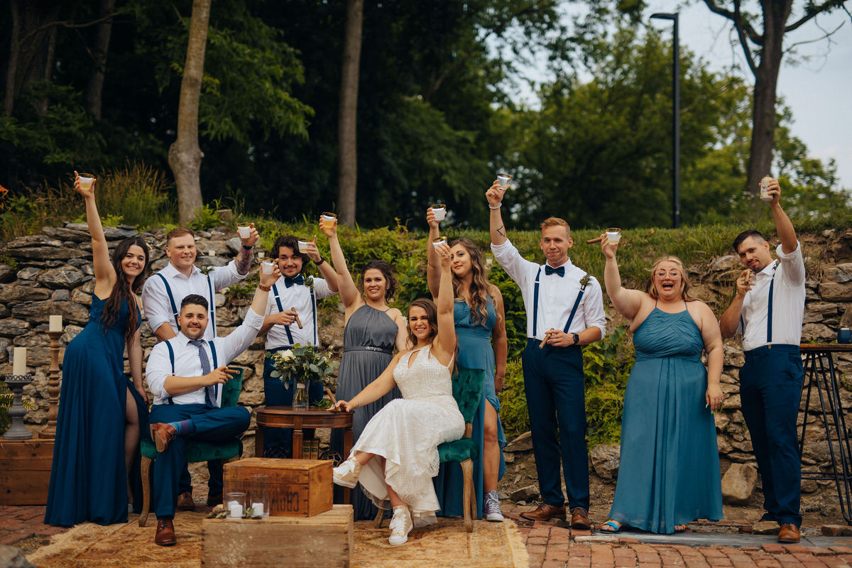 couple and wedding party holding drinks up cheersing 