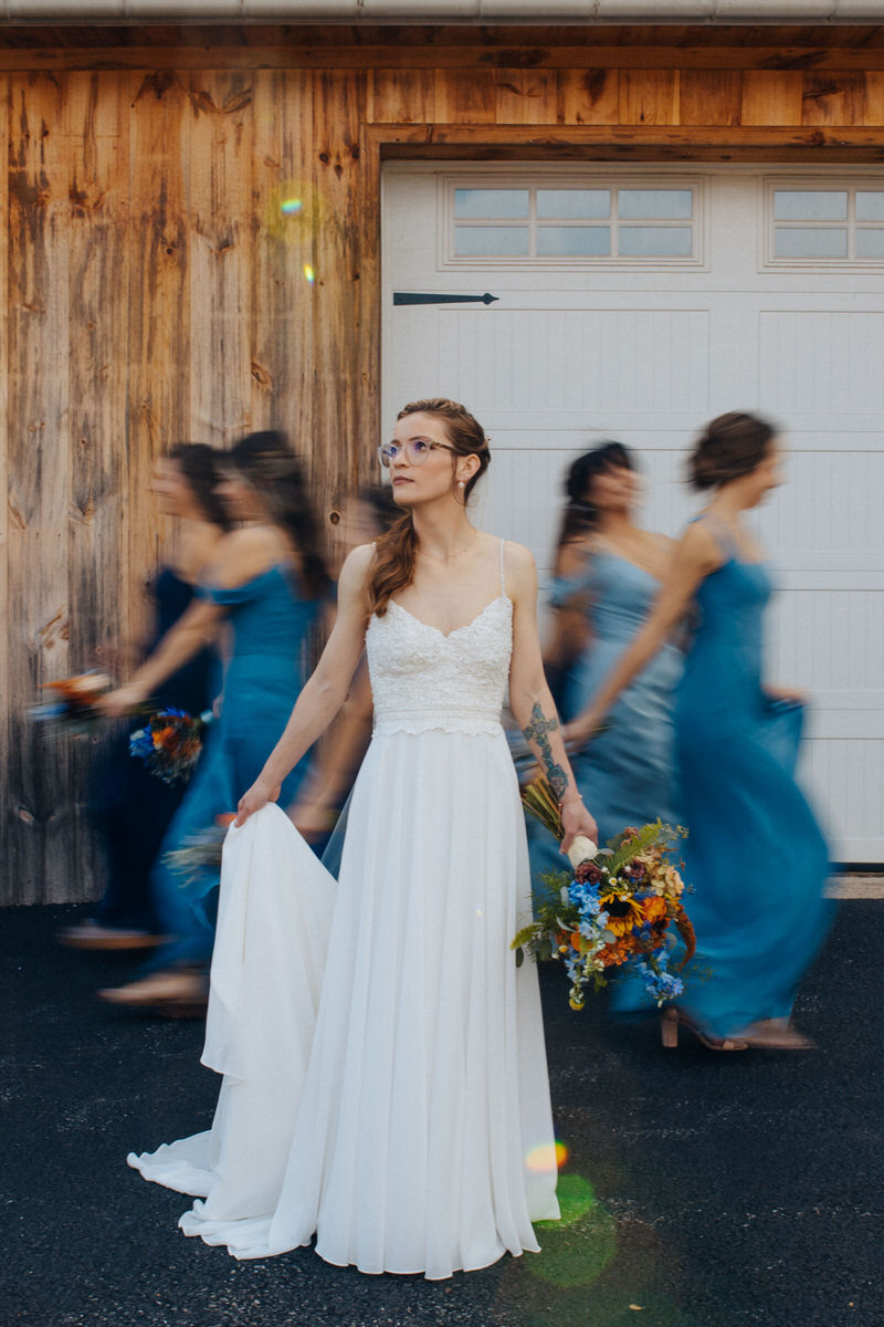 celebrant holding their dress with one had with their wedding party walking behind them slightly blurred out