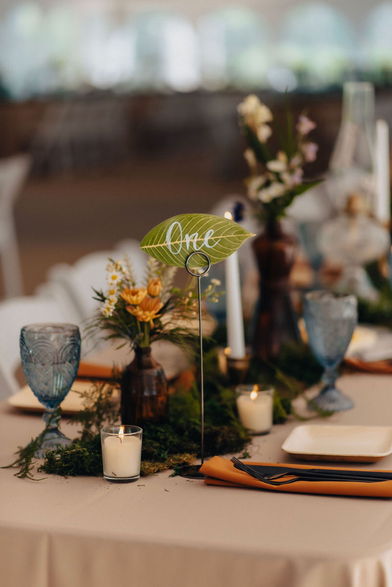 wedding reception table with a green leaf with the words one on it 