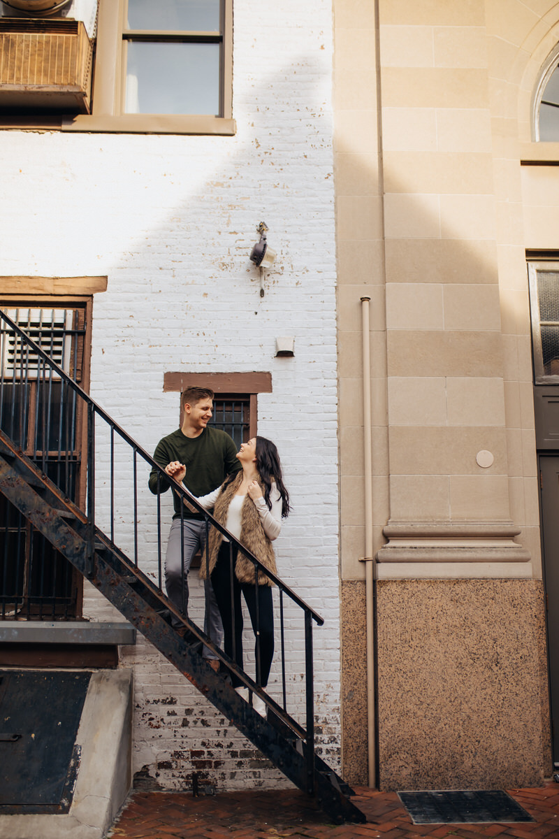 couple standing on a staircase outside looking at each other 