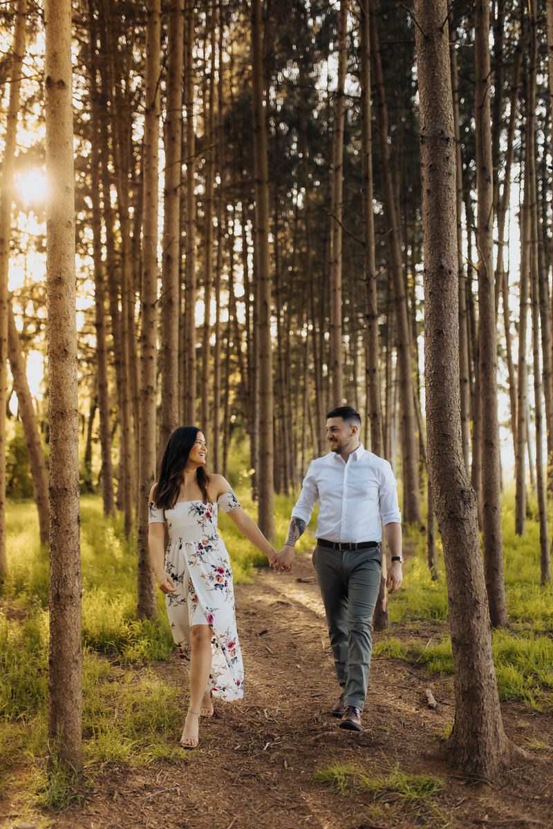 couple holding hands and walking along trail in a forest