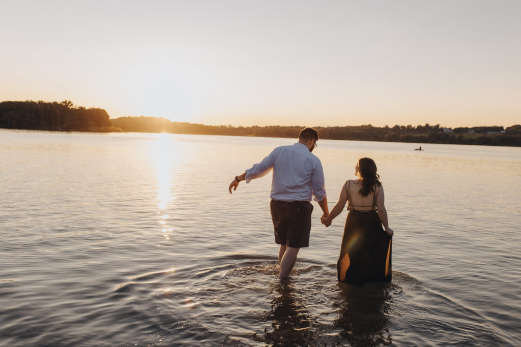couple holding hands and walking in shallow water