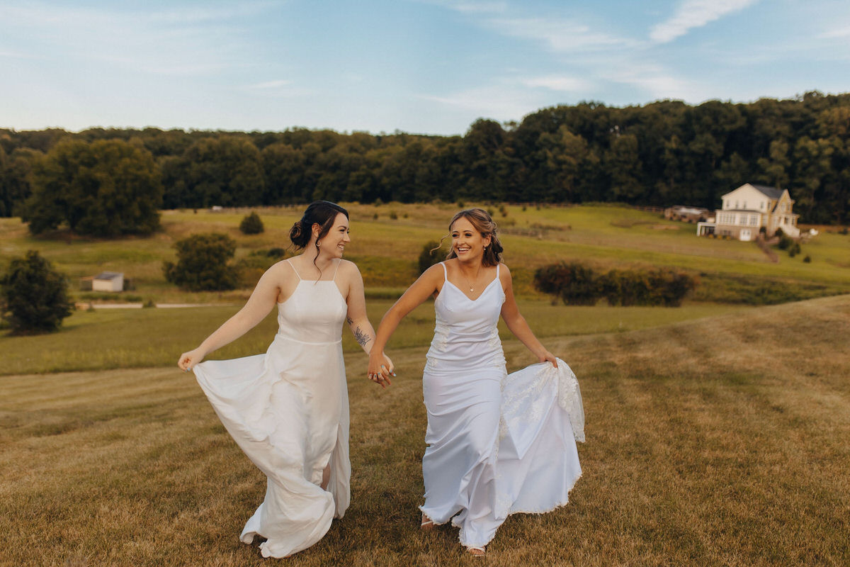 wedding couple holding hands and walking through field