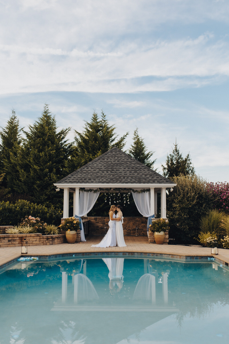 wedding couple about to kiss in front of a pool 