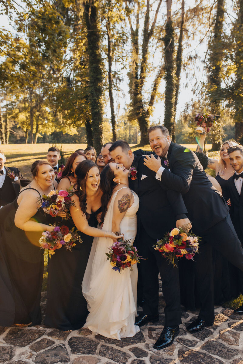 wedding couple kissing in front of their wedding party