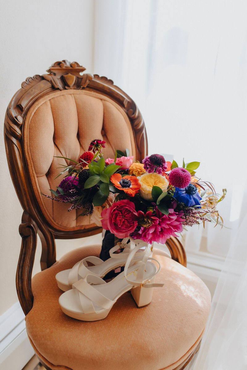 vibrant flowers and white shoes on a vintage chair 