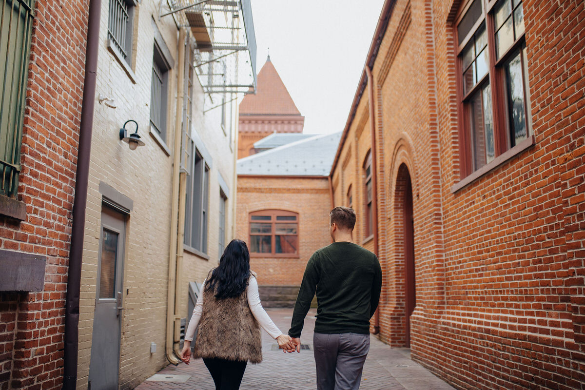 couple walking down alley holding hands 