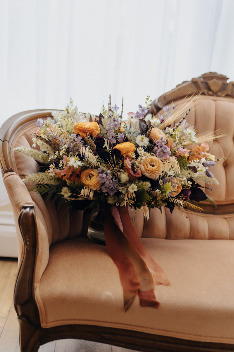 bouquet of flowers laying in the corner of a light brown couch