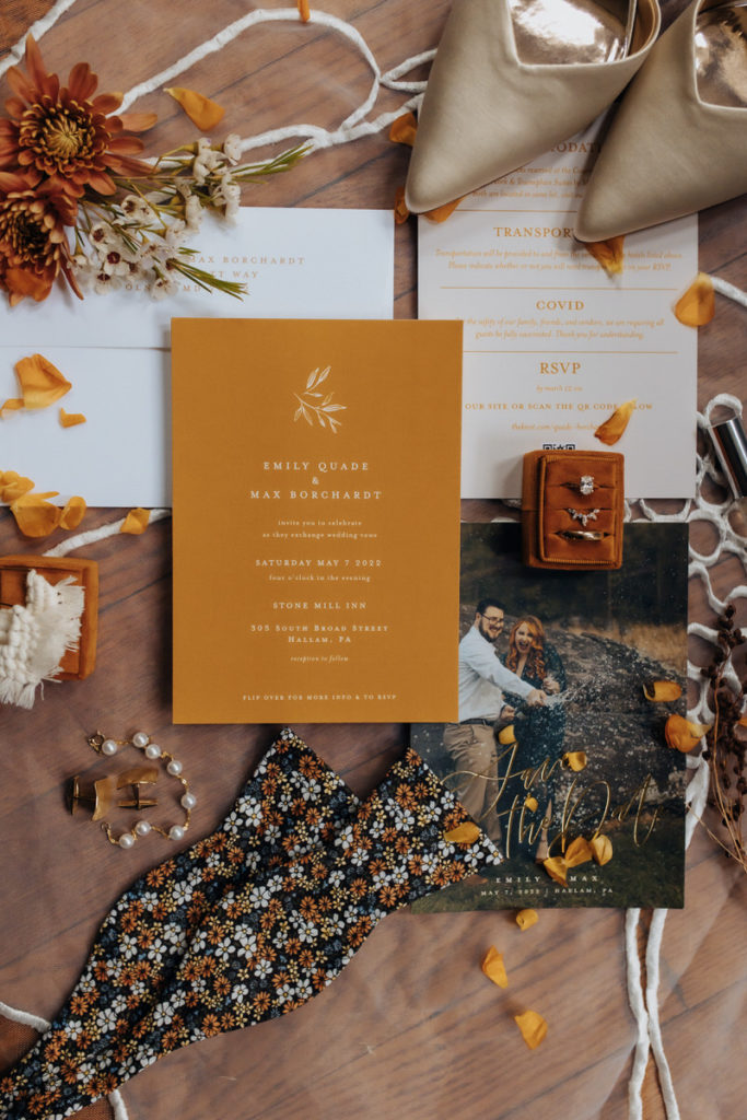 invitations, flowers, rings, shoes, and accessories laid out on a table 