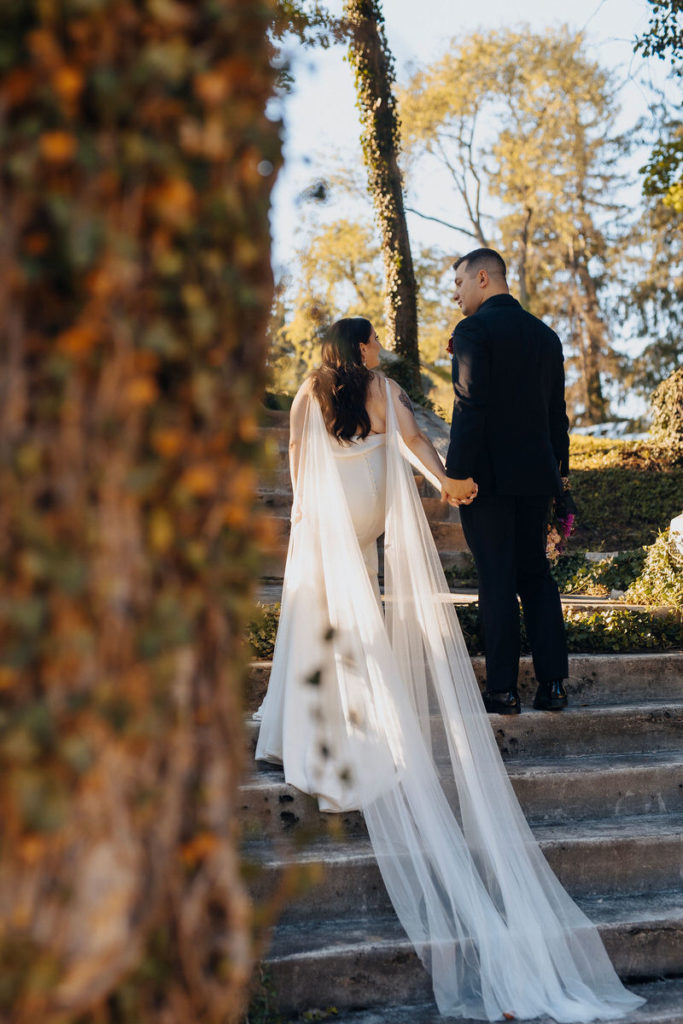 wedding couple holding hands and walking up a stone staircase