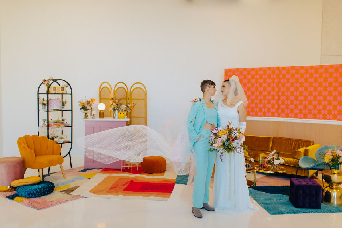 colorful wedding photography picture of a wedding couple standing in a room with colorful furniture and decor throughout