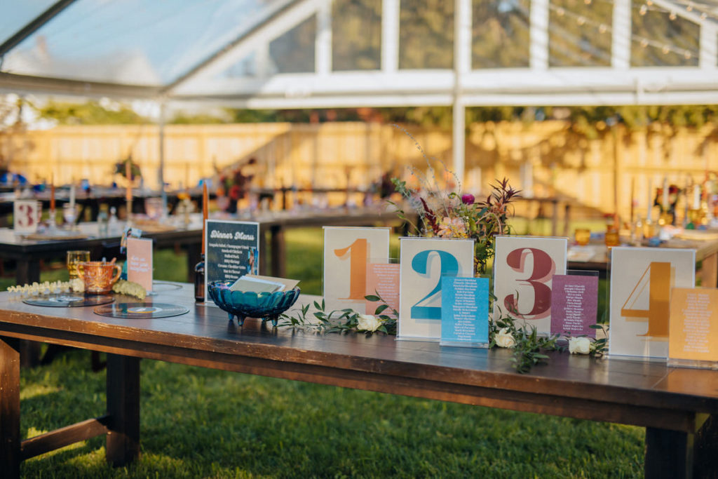 wooden table in an outdoor tent with colorful table numbers on them