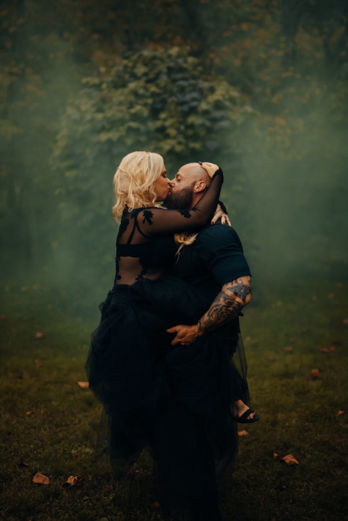 wedding couple holding each other and kissing with green smoke around them