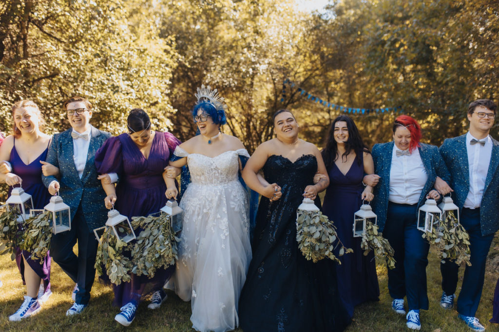 married couple and wedding party walking together with their arms linked 