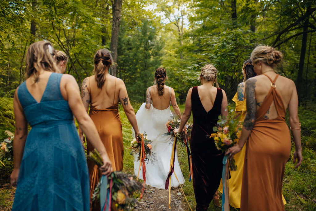 wedding participant and wedding parting walking in a forest while holding their bouquets