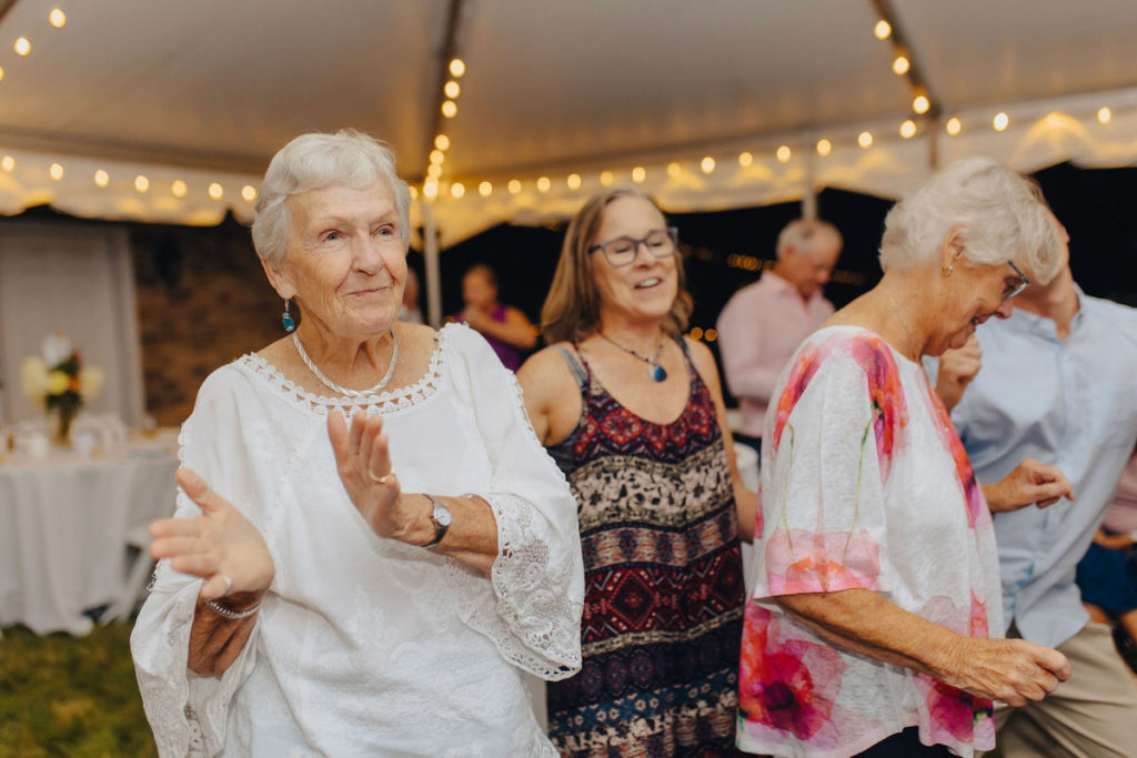 group of older wedding guests clapping and dancing at a reception
