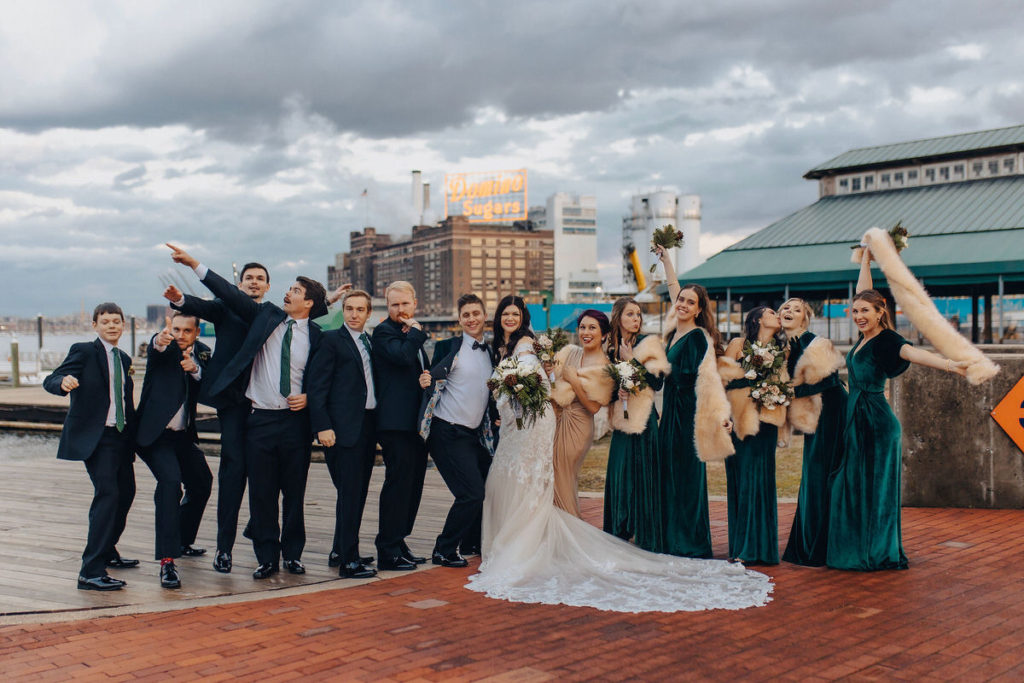 wedding party standing next to each other celebrating on a dock
