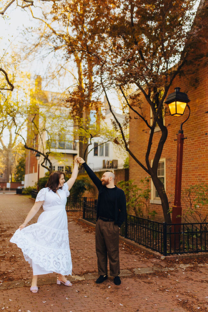 A couple dancing while standing on a city sidewalk. 