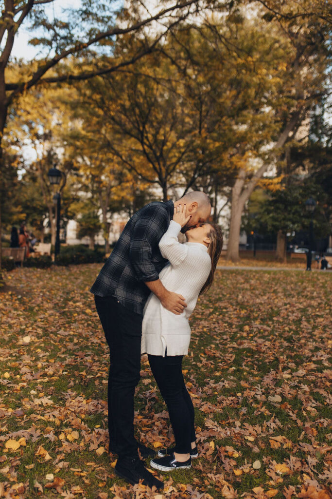 A couple kissing while standing in the middle of a park. 