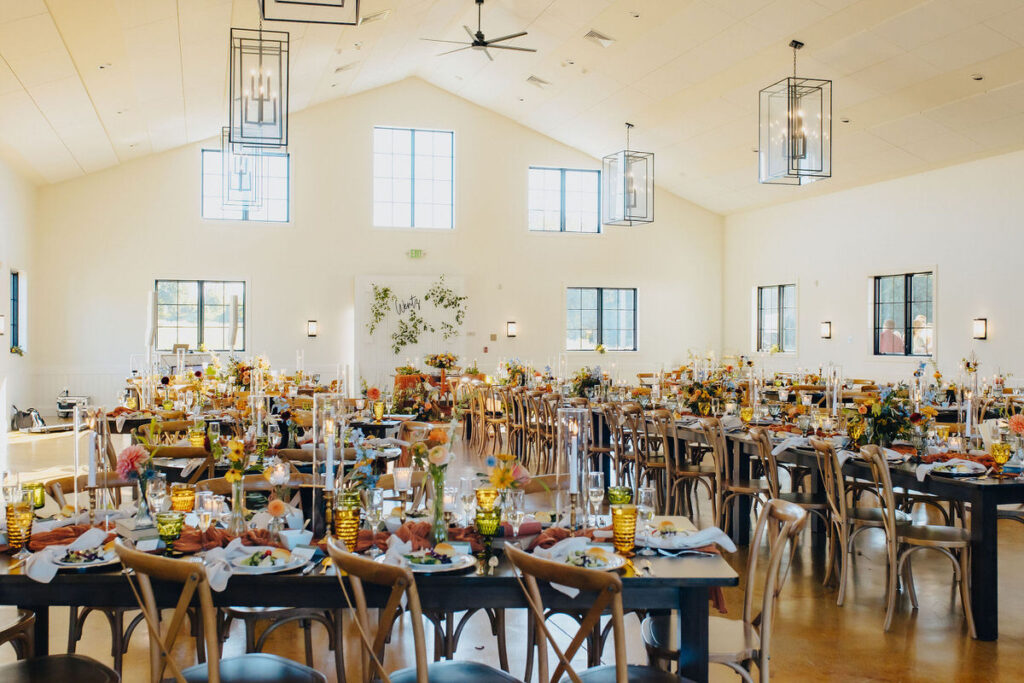 A large open building with wedding reception table and chairs set up. 
