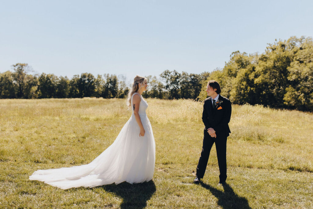 A bride and groom in an open field during their first look. 