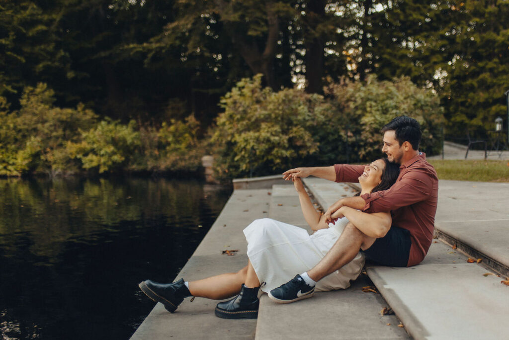 A couple sitting on a staircase together in front of a lake. 