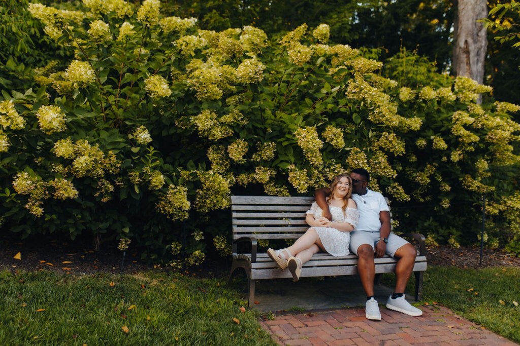 A couple sitting on a bench together in a garden. 