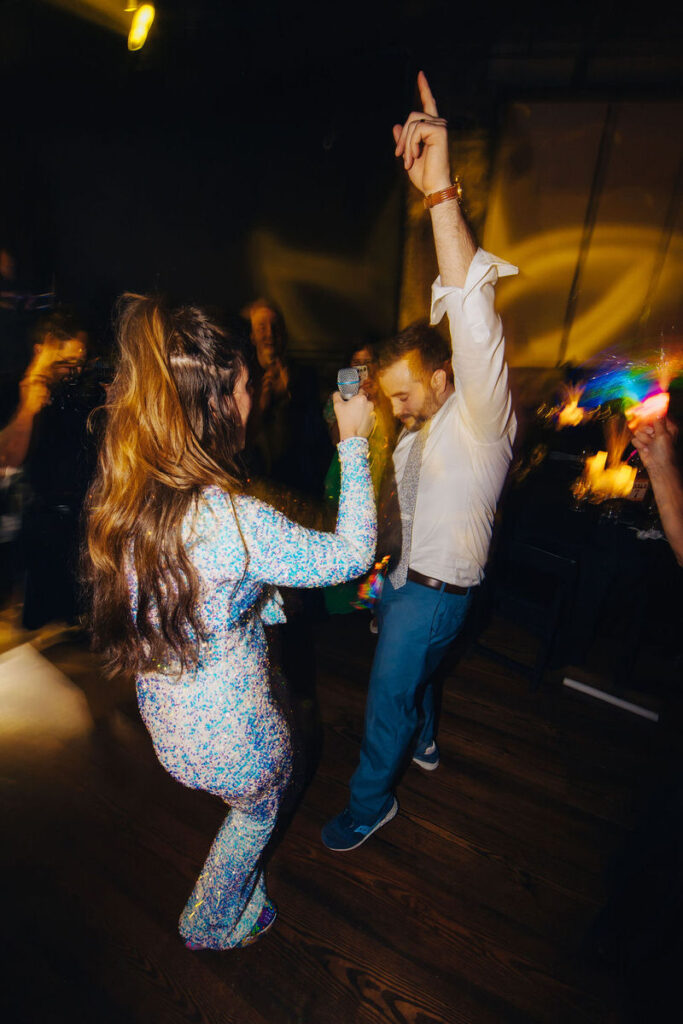 An individual pointing upwards triumphantly while dancing, with a blur of motion and light surrounding them.
