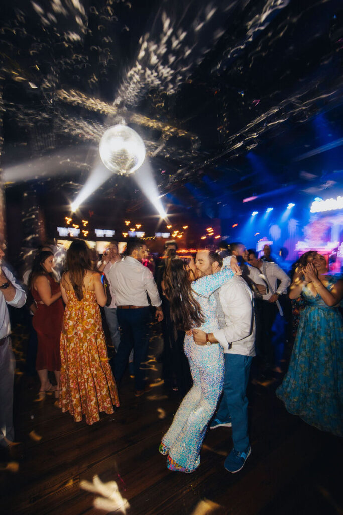 A glittering disco ball casting patterns over a crowd on a dance floor.
