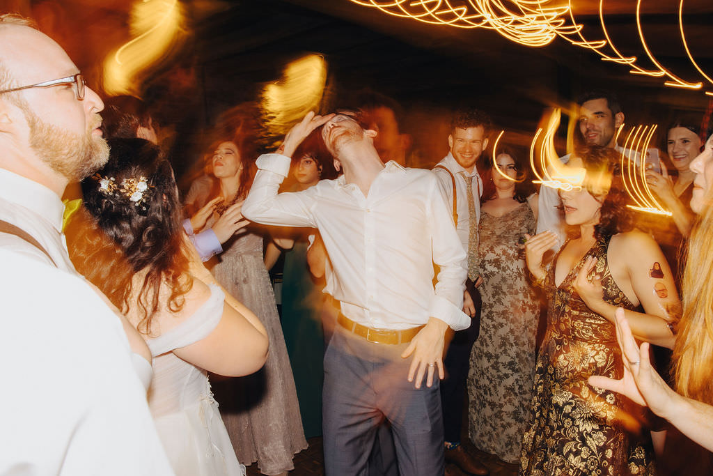 Partygoers raising their arms in a dance, with swirls of golden light adding to the festive atmosphere.
