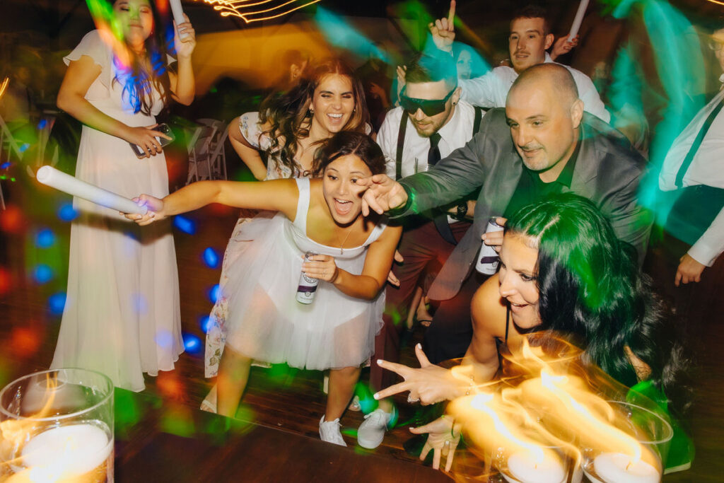A lively party scene with guests dancing and waving glow sticks, creating a fun and energetic atmosphere.