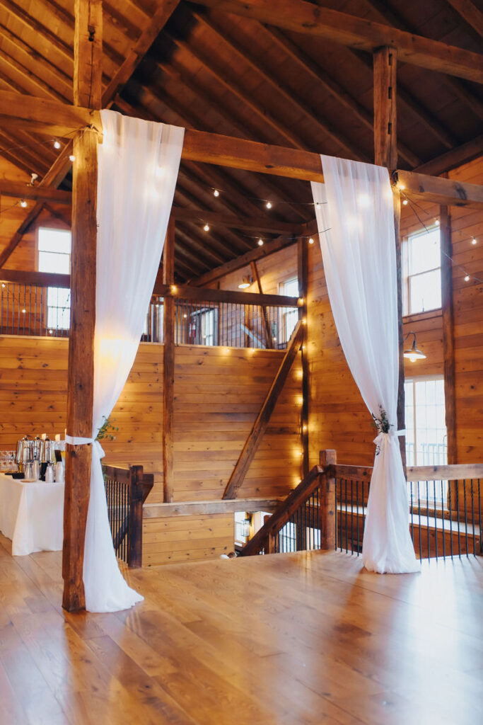 White drapes hanging down on either side of a wooden staircase in a lodge. 