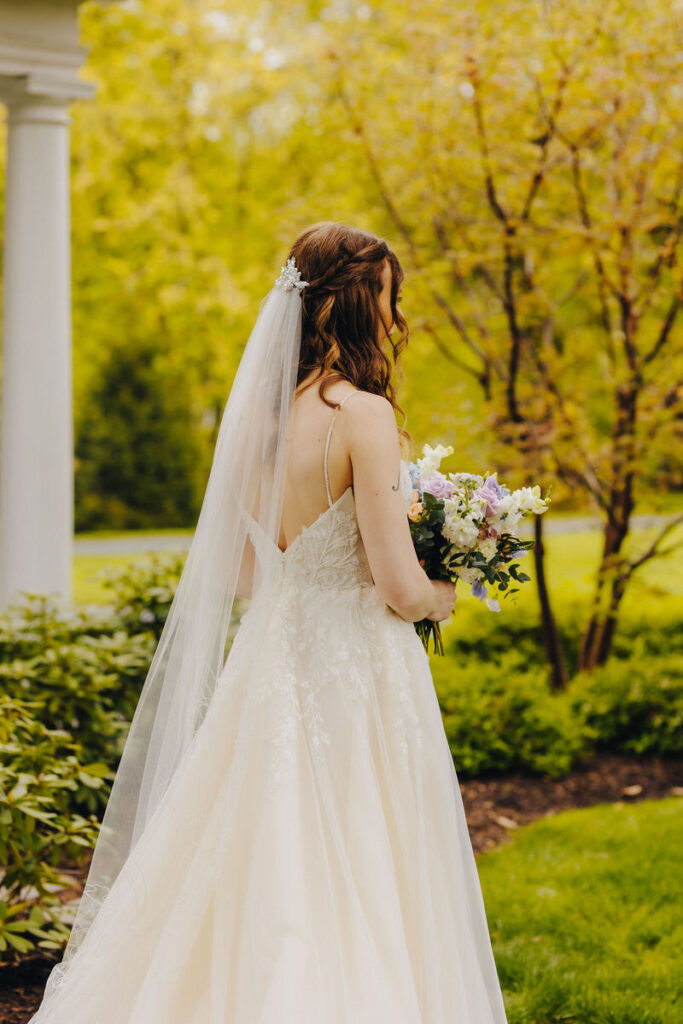 A bride holding a bouquet of flowers while standing outside. 
