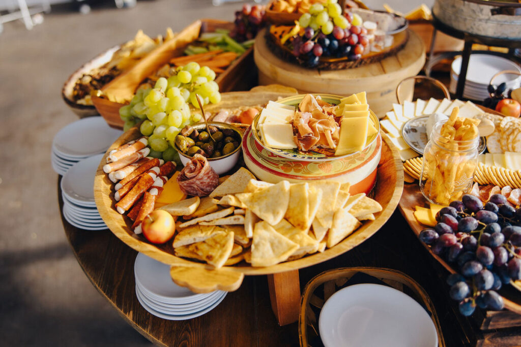A lavish charcuterie spread with an array of cheeses, meats, crackers, and fresh fruit elegantly arranged on wooden tiered stands