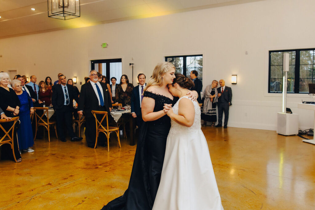 A heartfelt first dance moment at a wedding reception, with guests surrounding the dancing couple