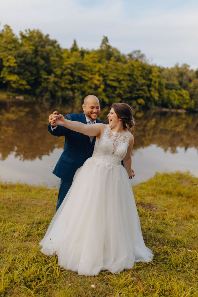 A newlywed couple dancing next to a lake
