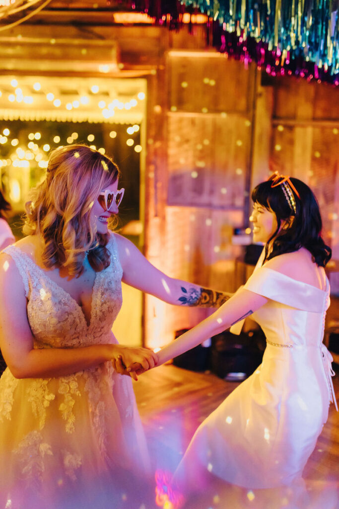 Two brides dancing with disco lights on 
